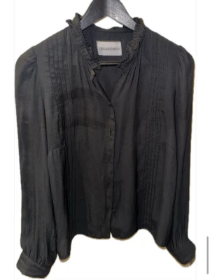Zadig&voltaire blus svart storlrk m - Tunt tyg med fina detaljer både uppe vid halsen och på tröjan. Går att knäppa med knappar i mitten och har även en varsinn knapp på vardera ärm längst ner.  Lite sliten vid knapparna invändigt - detta syns inte vid användning   Passform: lite pösig men ändå figursydd - storlek M men passar även S om man vill ha den löst sittande. Buda!