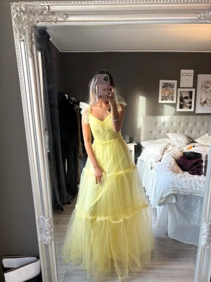 Gul balklänning - Säljer en så fin gul balklänning i tyll med volangdetaljer och v-ringad hals. Såå fin i ryggen. Aldrig använd. 