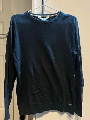 Svart långärmad tröja från H&M - En svart långärmad tröja från H&M med rund hals och ribbade muddar. Tröjan har en enkel design med en liten NYCAVE-label vid nederkanten. Perfekt för chill dagar och passar till det mesta. Materialet är mjukt och känns skönt mot huden.