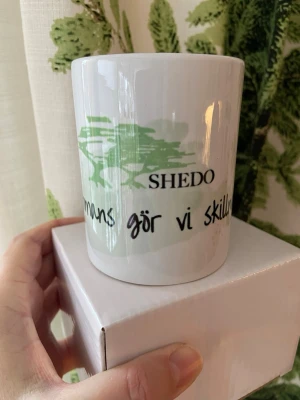 Ny mugg från SHEDO - Bilderna visar en vit mugg med grönt tryck och texten 'SHEDO Tillsammans gör vi skillnad'