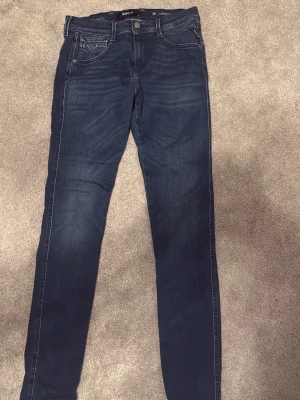 Replay jeans blå slim fit 30/34 - Snygga mörkblå jeans från Replay i modellen skinny fit. Klassisk femficksdesign med dragkedja och knapp, samt Replay-logga på bakfickan. Jeansen är gjorda i stretchigt bomullsmaterial för skön passform och har smal siluett hela vägen ner.  Nypris: ca 1700 kr. Extremt bra skick och inga tecken på användning.
