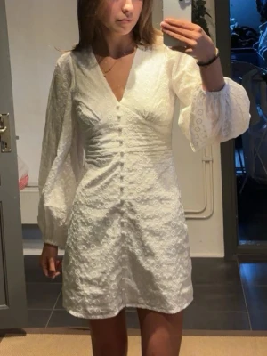 Vit kort klänning med puffärmar - Superfin vit kort klänning från bubbleroom med v-ringning, puffiga långärmar och broderade blommor i tyget. Perfekt för sommarens alla tillfällen! Aldrig använd med prislapp, säljer då den är lite liten. Nypris:759kr💓