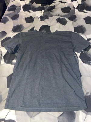 Grå t-shirt från Sail Racing - Säljer en grå t-shirt från Sail Racing i storlek S. T-shirten har korta ärmar och ett diskret Sail Racing-tryck vertikalt på framsidan. Materialet känns mjukt och är troligtvis bomull, perfekt för chill dagar. Rund halsringning med snyggt band på insidan.