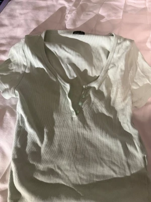 Ljusgrön topp🍈🍋‍🟩 - Säljer en ljusgrön ribbad topp från Gina Tricot i storlek M. Toppen har korta ärmar, v-ringning och fyra små knappar framtill. Materialet är mjukt och stretchigt, perfekt för vår och sommar. Enkel och snygg att matcha med jeans eller kjol.🍈💫
