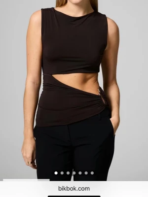 brun omlott topp med cut-out från Bik Bok - Säljer en brun omlott topp från Bik Bok med cool cut-out detalj i midjan och en silvrig metalldetalj. Perfekt festtopp. ❣️Lånade bilder❣️