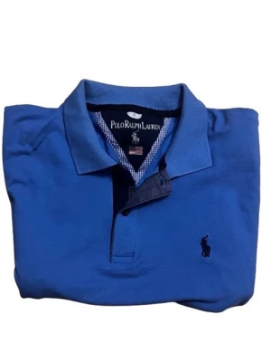 Blå Polo Ralph Lauren pikétröja - Tröjan passar exakt som en m vet inte Vrf d står L ni kan kolla måtten på bilden.Snygg blå pikétröja från Polo Ralph Lauren med klassisk krage och korta ärmar. Tröjan har den ikoniska broderade loggan på bröstet och knappar vid halsen. Perfekt för dig som gillar stilren och sportig look.