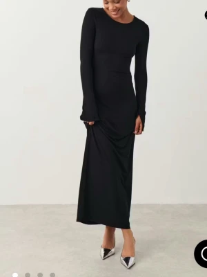 Svart långärmad maxiklänning Gina Tricot - En stilren svart långklänning från Gina Tricot i mjukt material. Klänningen har lång ärm, rund halsringning och en figurnära passform som ger en clean look. Perfekt för dig som gillar minimalistisk stil och vill ha något enkelt men snyggt.