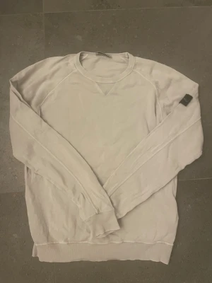  Långärmad tröja Stone Island - Säljer en beige långärmad tröja från Stone Island Junior med den klassiska loggan på ärmen. Tröjan har rund hals och ribbade muddar vid ärmslut och nederkant. Perfekt för dig som gillar clean och stilren streetwear. Den har två pyttesmå hål som ni ser på bilderna. Annars är allt på topp! Pris går att diskutera☺️