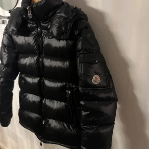 Svart pufferjacka Moncler - Skriv privat för mer information, kan diskutera pris vid snabbt köp. Säljer en svart pufferjacka  Moncler med glansig finish och huva. Jackan har dragkedja framtill, två sidofickor med dragkedja och en ficka på ärmen med Moncler-logga. Perfekt för kalla dagar och har en riktigt schysst streetstil.