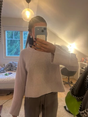 Ljusrosa stickad tröja med vida ärmar - Supermysig ljusrosa stickad tröja med breda ribbade muddar och avslappnad passform. Tröjan har rund halsringning och är lite croppad, perfekt till både jeans och mjukisbyxor. Enkel och stilren design som är lätt att matcha.