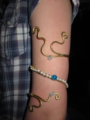 Unik guldarmcuff med pärlor och blå detaljer -  handgjord armring i guld med snirkliga former. Dekorerat med vita pärlor och en stor blå pärla i mitten och små ljusblå stenar. småsmå repor från tången kan finnas men absolut inget man tänker på!!