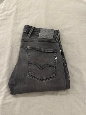 Replay Anbass svarta jeans - Snygga svarta Replay Anbass jeans med klassisk femficksdesign och diskret Replay-logga på fickan. Jeansen har en slim passform och är tillverkade i mjukt jeansmaterial med lite stretch för extra komfort. Perfekt för dig som gillar stilrena och moderna jeans. Strl 31,32