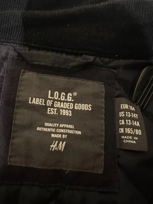 Mörkblå quiltad jacka från H&M L.O.G.G. - Säljer en mörkblå quiltad jacka från H&M L.O.G.G. Jackan har dragkedja framtill, två fickor med lock och tryckknappar samt hög krage. Snyggt rutmönster över hela jackan och en stilren look som passar perfekt till höst och vår. Modellen är 178 cm o väger 75 kg