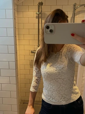 Vit spetsblus med trekvartsärm - Säljer en vit blus i spets med blommigt mönster och trekvartsärm. Toppen har rund halsringning och är figurnära i passformen.  Den är egentligen köpt på barn avdelningen, men passar mig som oftast har S.