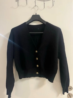 Svart stickad kofta med knappar - Säljer en svart stickad kofta med V-formad hals.
