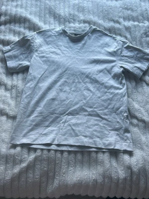 Vit loose fit t-shirt från H&M - Säljer en enkel och clean gråvit t-shirt från H&M i loose fit-modell. T-shirten har rund hals och korta ärmar, perfekt avslappnad stil. Materialet är mjuk bomull som känns skönt mot huden. Passar dig som vill ha en basic tee med lite extra space.