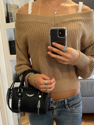 Offshoulder stickad tröja - Beige stickad tröja med bred offshoulder-design. Tröjan är croppad och har långa ärmar. 