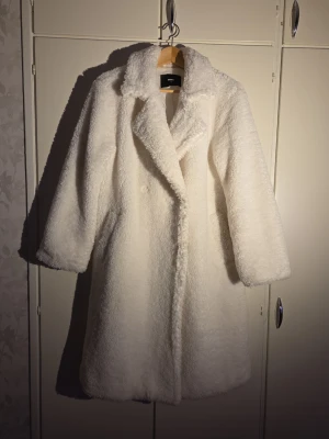 Vit teddyjacka från Bik Bok - Säljer en fluffig och mjuk vit teddyjacka från Bik Bok i storlek S. Jackan har en oversized passform, bred krage och långa ärmar. Perfekt för dig som vill ha en cozy vibe under kyliga dagar. Materialet är syntet och jackan är helfärgad utan mönster.