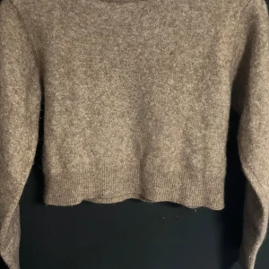 Beige stickad tröja från Zara - Säljer en beige stickad tröja från Zara i storlek S. Tröjan har en croppad passform med ribbad nederkant och långa ärmar. Perfekt för dig som gillar en enkel och stilren look med mjukt material.