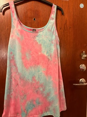 Pastellfärgad linne från SHEIN - Säljer ett linne från SHEIN i storlek M med snyggt batikmönster i rosa och ljusblå toner. Linnet har breda axelband och ärmlös design, perfekt för varma dagar. Materialet är mjukt och skönt, troligtvis bomull eller polyester.