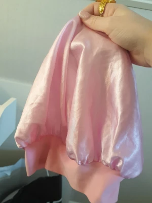 Ljusrosa sovmössa - Säljer en ljusrosa sovmössa i glansigt satinliknande material.  Perfekt för dig som vill vakna på morgonen utan frissigt hår