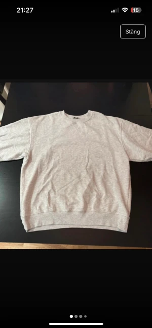 Ljusgrå sweatshirt i bomull - En enkel och stilren ljusgrå sweatshirt med rund hals och ribbade muddar. Tröjan har en klassisk passform och är tillverkad i mjuk bomull, perfekt för chill dagar. Passar dig som gillar basic och neutrala färger.