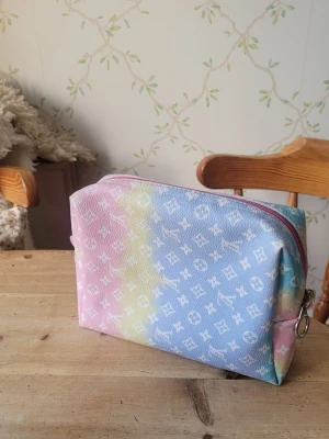 Pastellfärgad necessär med dragkedja make up - Säljer en snygg necessär från i pastellfärger med rosa, blått och gult. Funkar förstås som en clutch eller så men jag har haft smink i min. 