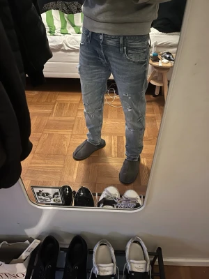 Jeans med slitningar från Jack and Jones  - Snygga Jack and Jones  jeans med slitningar och lätt tvättad look. Modellen har normal passform och klassisk femficksdesign. Perfekta för en avslappnad streetstil och tillverkade i mjukt bomullsjeansmaterial.