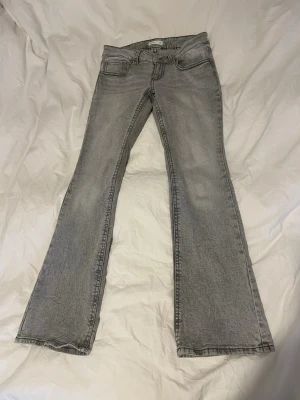 Grå bootcut jeans från Perfect Pants - Snygga grå bootcut jeans från Gina Tricot med klassisk femficksdesign och knappgylf. Jeansen har en lätt utsvängd passform nedtill och är tillverkade i mjukt denimtyg som ger en bekväm känsla. Perfekta för dig som gillar en retroinspirerad look. Storlek 40 men passar även storlek 38. Pris går att diskutera!