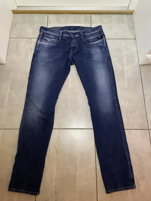 Mörkblå Replay Anbass jeans - Snygga mörkblå Replay Anbass jeans med femficks design. Jeansen har normal passform och raka ben, tillverkade i mjukt bomullsjeansmaterial. Perfekta för en avslappnad och stilren look. Sitter bra på: 175-184 vikt 60-70 kg.