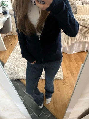 Blå bootcut jeans Nelly - Säljer ett par klassiska blå bootcut jeans med snygga kontrastsömmar och detaljerade bakfickor. Jeansen har normal passform och är tillverkade i ett mjukt jeansmaterial som sitter skönt hela dagen.