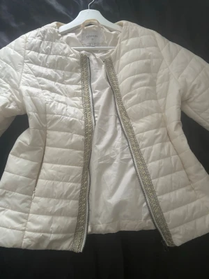 Vit quiltad cardigan jacka från Cream - Snygg vit quiltad cardigan jacka från Cream med dekorativt band längs öppningen. Jackan har lång ärm och en lätt oversized passform. Perfekt att slänga över en t-shirt för en chill men ändå stilsäker look. Aldrig använd. Pris går att diskuteras🩷