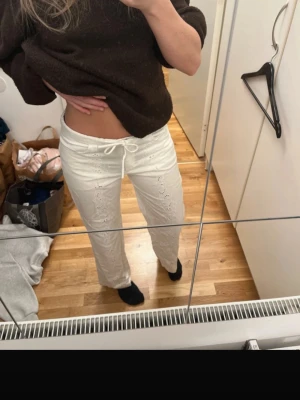 Vita broderibyxor med snörning - Säljer ett par vita broderibyxor med snygg snörning i midjan och broderade detaljer längs benen. Byxorna har rak passform och passar för runt 160 och kortare. Aldrig använda