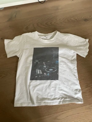 Vit t-shirt med DJ-print och text -  stort DJ-motiv på framsidan och texten 'NOT EVERYONE UNDERSTANDS HOUSE MUSIC' på ryggen. Klassisk passform och rund hals. Perfekt för dig som älskar musik och vill sticka ut lite extra.