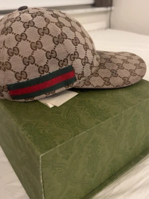 Gucci GG Supreme keps beige/brun - Tjena, säljer nu min Gucci keps som inte är till användning längre. Kepsen är i färgen beige och brunt med klassiskt GG mönster över hela kepsen. Det som ingår är box och kvitto. Mitt pris är 1799kr. Hör av dig vid minsta fundering 😊