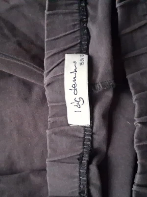 Svarta mjukisbyxor från I dig denim - Svarta mjukisbyxor från I dig denim med elastisk midja och raka ben. Sköna och enkla att matcha till olika stilar. Perfekta för chill dagar eller när du vill ha det bekvämt. Tillverkade i mjukt material som känns nice mot huden.