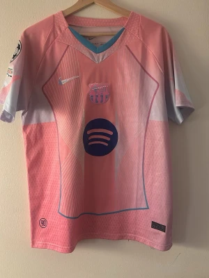 Barça rosa matchtröja Bonmatí #14 - Säljer en rosa och ljusblå FC Barcelona matchtröja från Nike med Bonmatí och nummer 14 på ryggen. Tröjan har klubbmärke, Nike-logga och Spotify som sponsor framtill. Säljer pågrund av att den är förstor. Pris går absolut att diskutera
