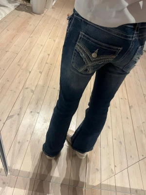 Mörkblå bootcut jeans med kontrastsömmar - Snygga mörkblå jeans med bootcut passform och tydliga kontrastsömmar. Bakfickorna har dekorativa detaljer och knappstängning. Jeansen har normal midja och är tillverkade i klassiskt denimtyg. Från Gina trikot köpta för 399