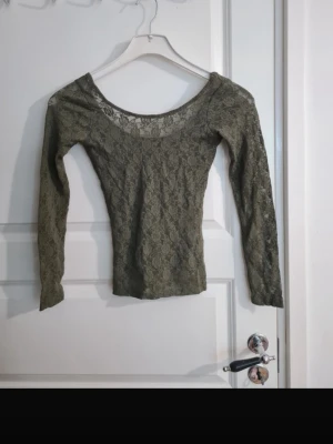 Olivgrön spetsblus med lång ärm - Säljer en olivgrön, figurnära topp i spets med långa ärmar och rundad halsringning. 