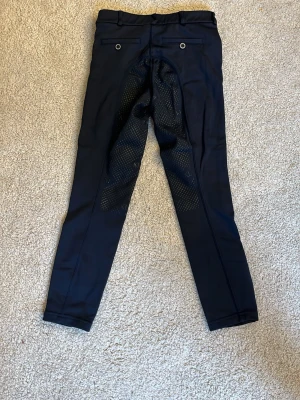 Mörkblå ridbyxor från kingsland - Snygga mörkblå fodrade ridbyxor från kingsland med helskoning i silikon för extra grepp. Byxorna har två bakfickor med knappar. 