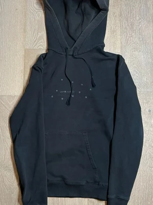 Navy hoodie från Saint Laurent - Snygg hoodie från Saint Laurent med diskret tryck av små stjärnor och logga på bröstet. Klassisk känguruficka framtill, justerbar dragsko i huvan och ribbade muddar. Perfekt för en avslappnad och trendig look. Passar S