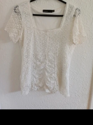 Vit spetsblus med snörning från Bik Bok - Söt vit blus från Bik Bok i spets med korta ärmar och snörning framtill. Blusen har en lätt transparent känsla och fina volangdetaljer längs kanterna. Perfekt för dig som gillar romantisk och feminin stil.