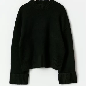 Svart stickad tröja Gina Tricot - Säljer en svart stickad tröja från Gina Tricot med breda ribbade muddar vid ärmslut, nederkant och halsringning. Tröjan har en avslappnad passform och är perfekt för lager på lager. Materialet känns mjukt och tjockt, vilket gör den extra mysig.