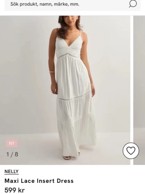 Vit långklänning från Nelly - Säljer en vit långklänning från Nelly med spetsdetaljer och v-ringad hals. Klänningen har smala axelband och en flowy passform som ger en romantisk känsla. Perfekt för sommarens alla tillfällen. Använd 1 gång under min konfirmation. 