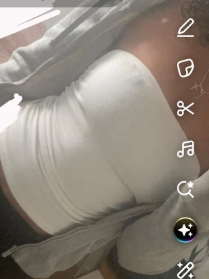 Vit bandeau tubtopp - Säljer en enkel och stilren vit bandeau tubtopp. Toppen är ärmlös och har en tight passform som sitter snyggt på kroppen. Perfekt att matcha med en hoodie eller jeans för en clean look.