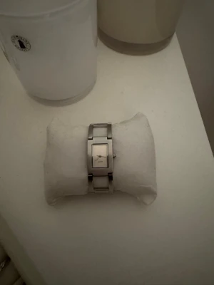 Silverfärgad rektangulär damklocka - Stilren damklocka i silverfärgat metallarmband med rektangulärt ur och vit urtavla. Minimalistisk design med diskreta visare och länkarmband som ger en modern känsla. Perfekt accessoar för dig som gillar enkel och tidlös stil. Obs batteriet behöver bytas🤎