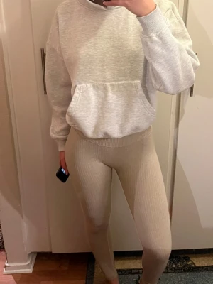 Beige ribbade träningsbyxor med hög midja - Säljer ett par snygga beige leggings med ribbad struktur och hög midja. De är tighta och stretchiga, perfekta för en chill vardagslook eller till träning. Materialet är mjukt och följsamt, och färgen är lätt att matcha med det mesta.