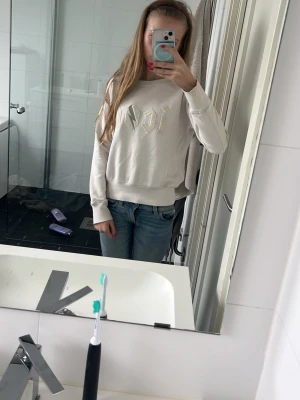 Vit sweatshirt med text från ICIW - Vit sweatshirt från hunkydory med broderad text framtill i beige nyans. Tröjan har rund halsringning, långa ärmar och ribbade muddar vid ärmslut och nederkant. Perfekt för en avslappnad och trendig look.