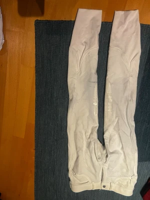 Vita ridbyxor från CRW - Snygga vita ridbyxor från CRW med silikongrepp på insidan av benen för extra fäste i sadeln. Byxorna har hög midja och detaljerade sömmar för en sportig look. Perfekta för dig som gillar ridning och vill ha stilrena byxor i stretchigt material.
