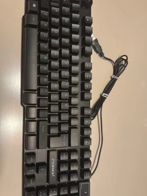 FOREV svart mekaniskt tangentbord - Säljer ett svart mekaniskt tangentbord från FOREV med USB-anslutning. Tangentbordet har klassisk layout med numerisk del och tydliga vita tecken på svarta tangenter. Perfekt för gaming eller skrivbordsarbete. Tillverkat i plast och har robust känsla.